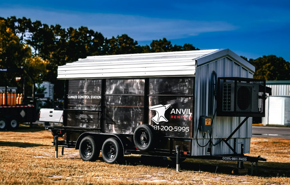 Three-quarter exterior of an Anvil Rentals climate control station trailer against a blue sky, showing the company branding and phone number on the side